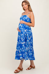 woman wearing a blue floral maternity dress, showcasing her baby bump, with spaghetti straps and a flowing skirt