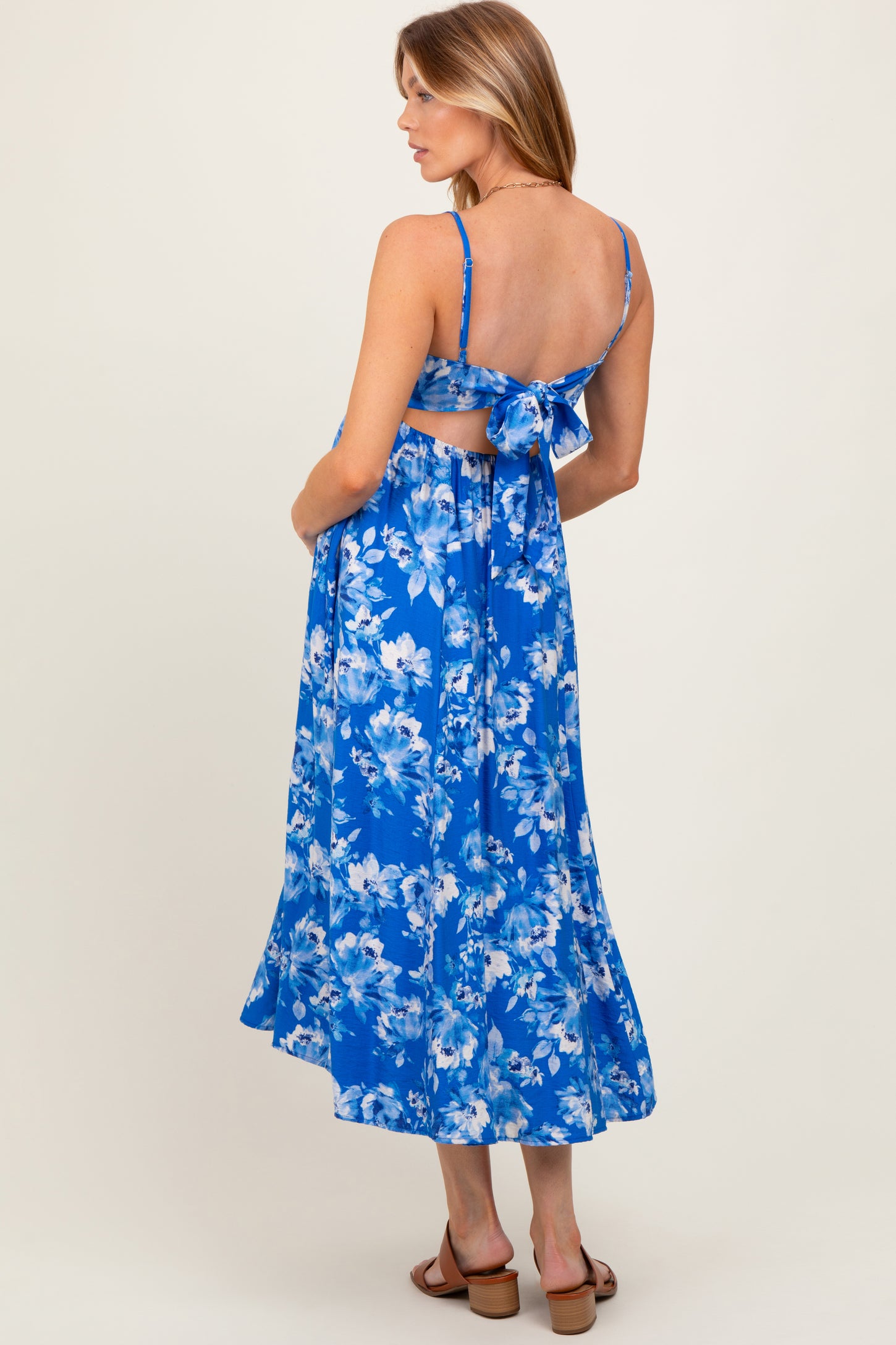 woman wearing a blue floral maternity dress with a back tie detail and a flowy skirt