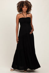 woman wearing a black strapless maternity maxi dress with a smocked bodice and holding her baby bump