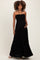 woman wearing a black strapless maternity maxi dress with a smocked bodice and holding her baby bump