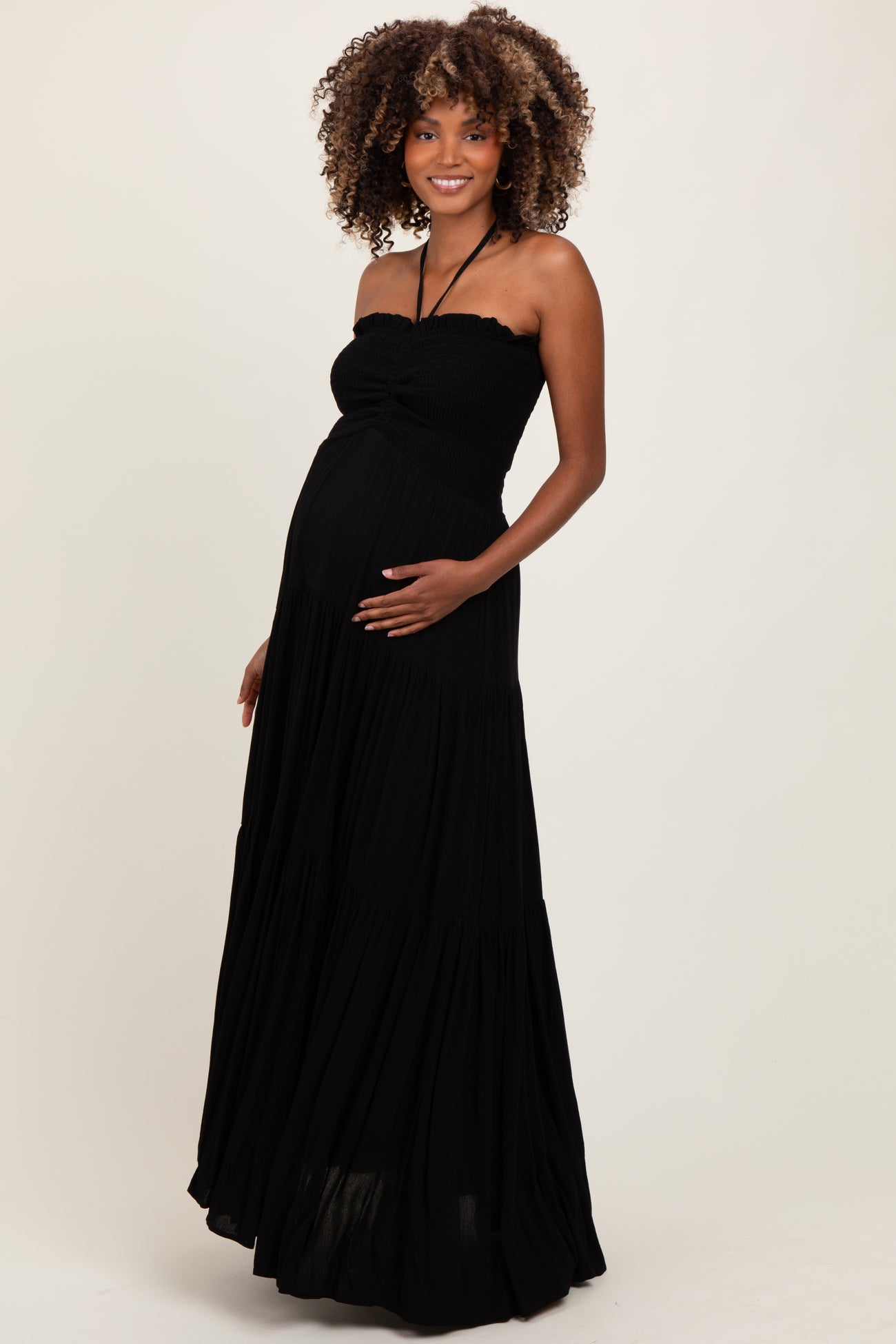woman wearing a black strapless maternity maxi dress and holding her baby bump