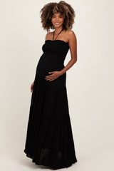 woman wearing a black strapless maternity maxi dress and holding her baby bump