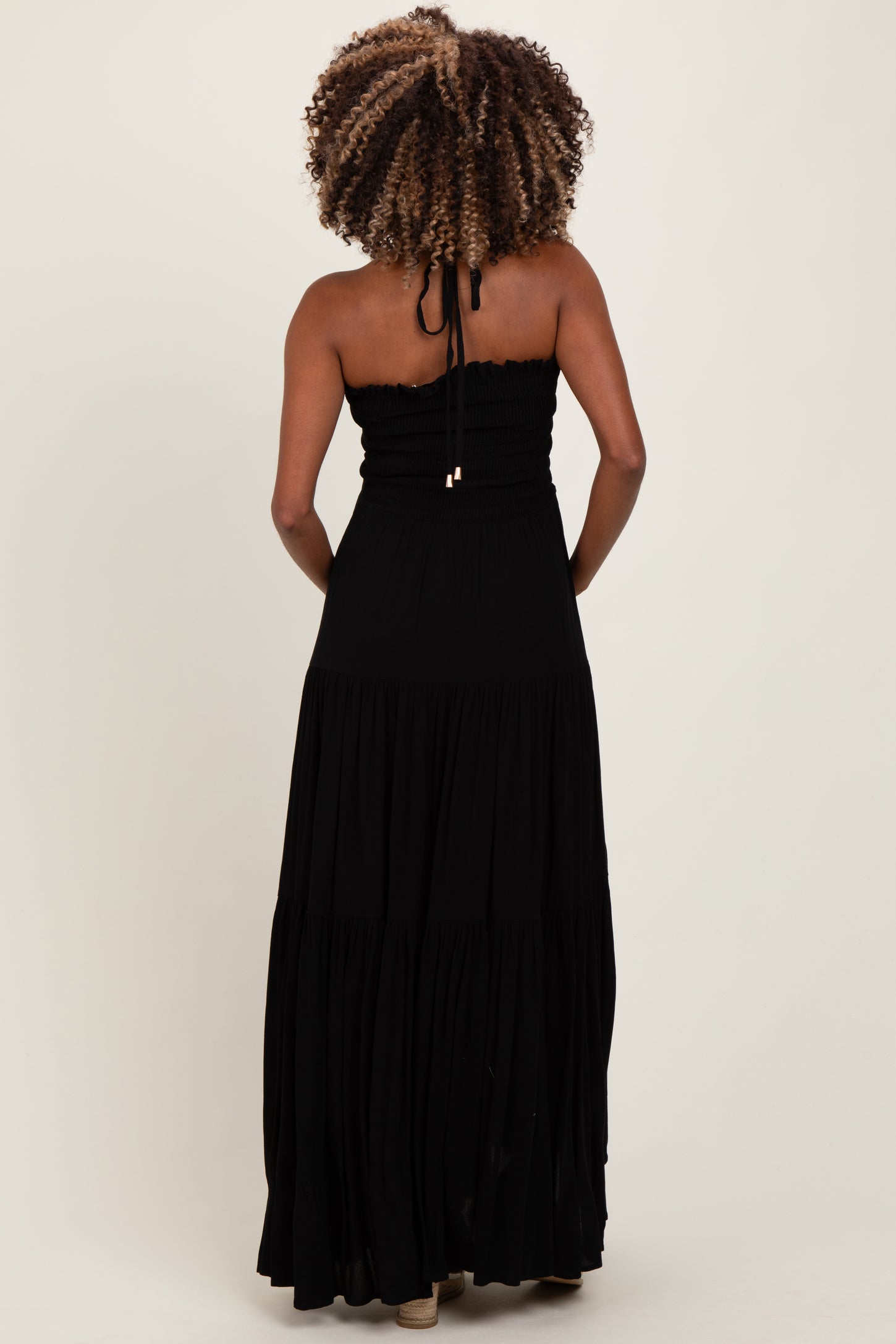 woman wearing a black strapless maxi maternity dress with a fitted bodice and tiered skirt from the back