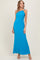 woman wearing a turquoise one-shoulder maxi dress with a floral embellishment on the shoulder