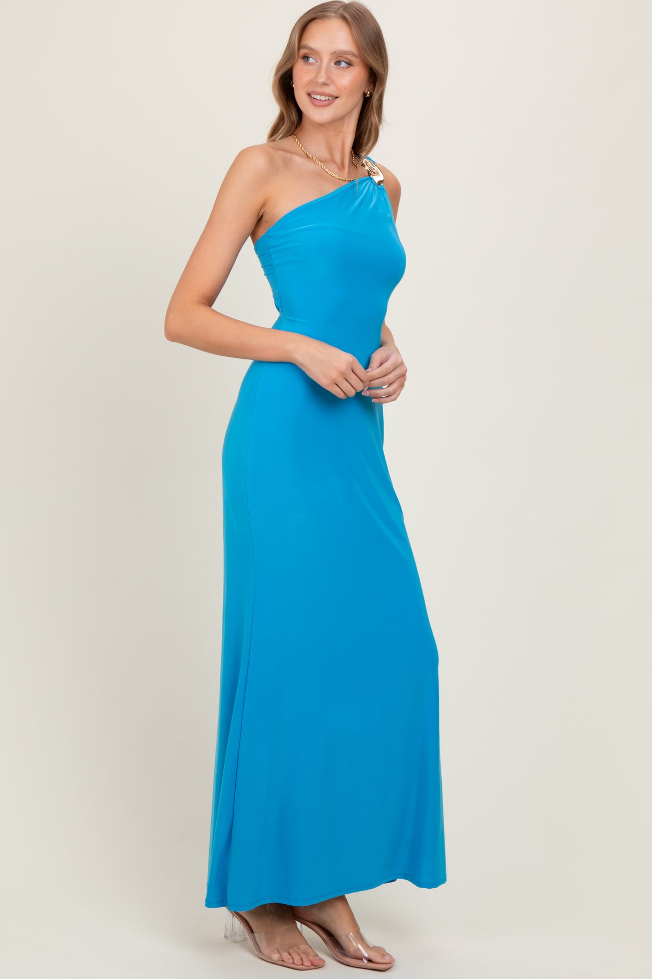woman wearing a bright blue one-shoulder maxi dress with a decorative strap detail