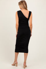 woman wearing a black maternity dress with a fitted silhouette and gathered details, facing away from the camera
