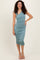 woman wearing a fitted teal one-shoulder midi dress with ruching details and a side slit