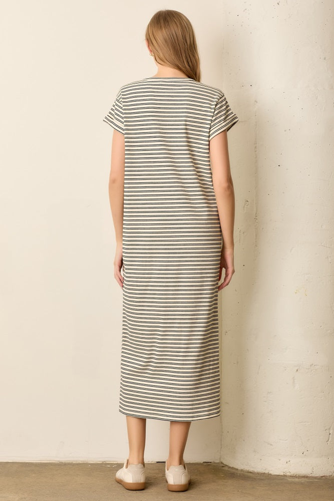 woman wearing a striped midi dress with short sleeves, seen from the back, styled with simple slip-on shoes