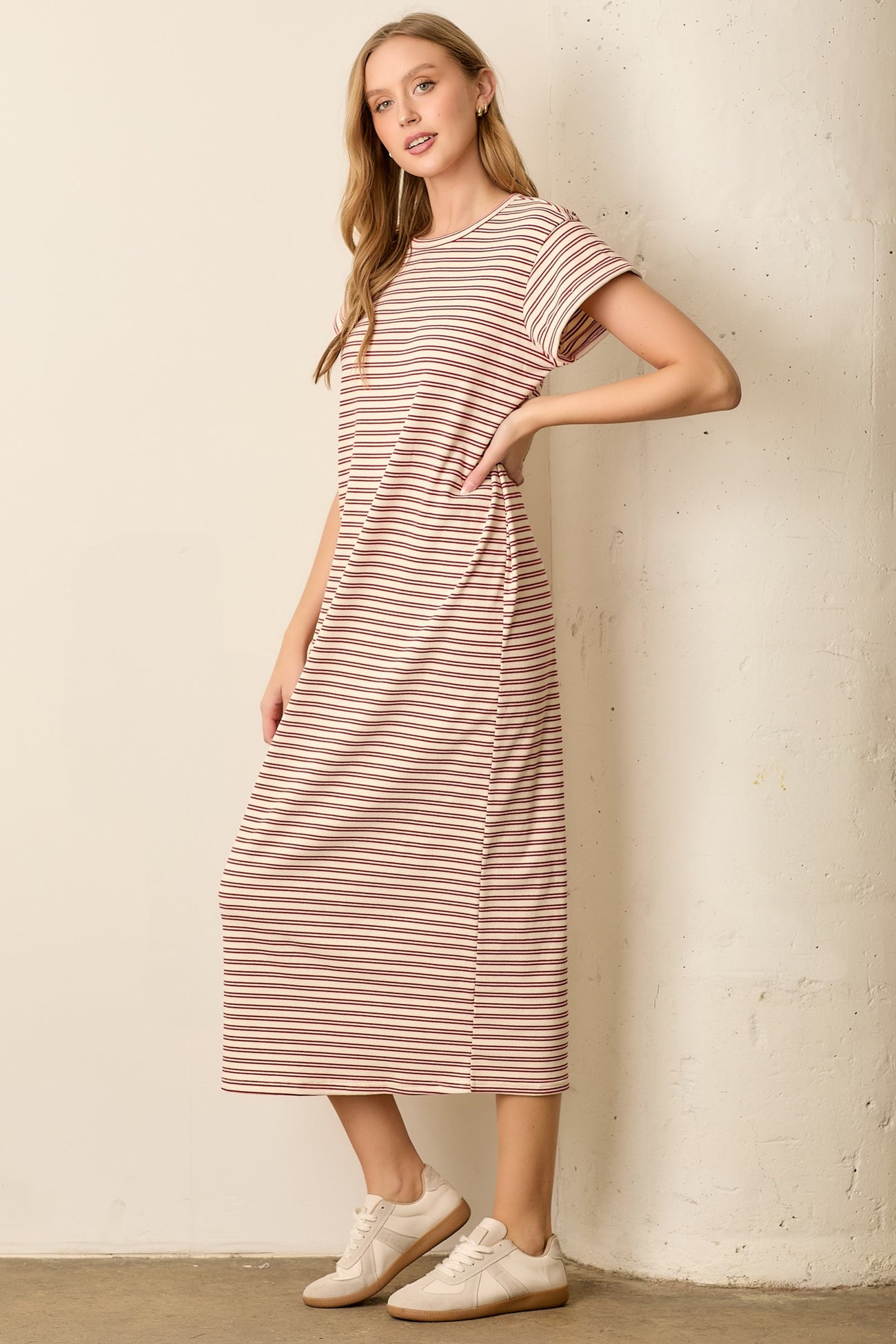 woman wearing a light pink and white striped midi dress with short sleeves and side pockets