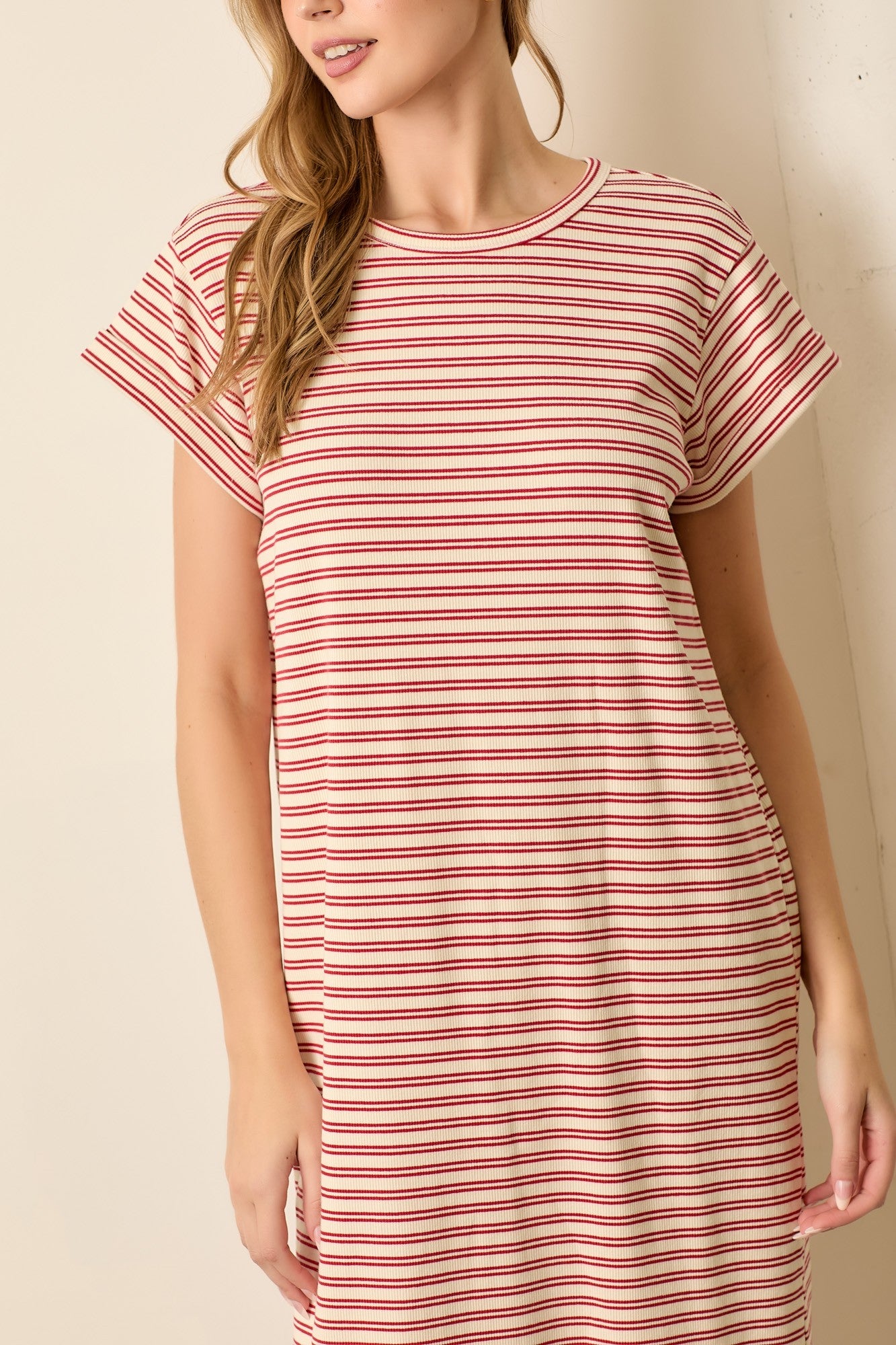 woman wearing a red and cream striped short sleeve t-shirt dress standing against a light background