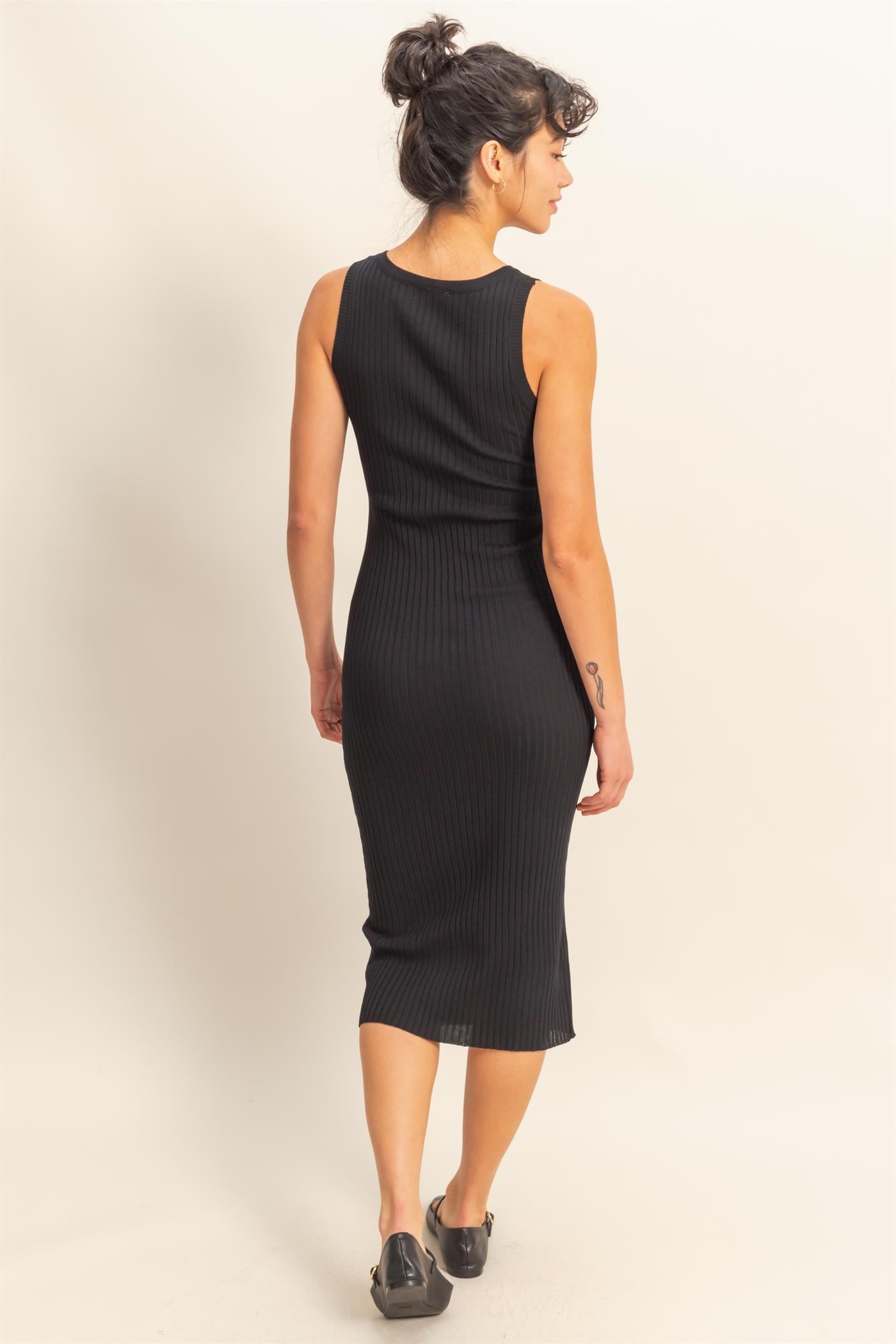 woman wearing a black ribbed midi dress with a fitted silhouette and sleeveless design