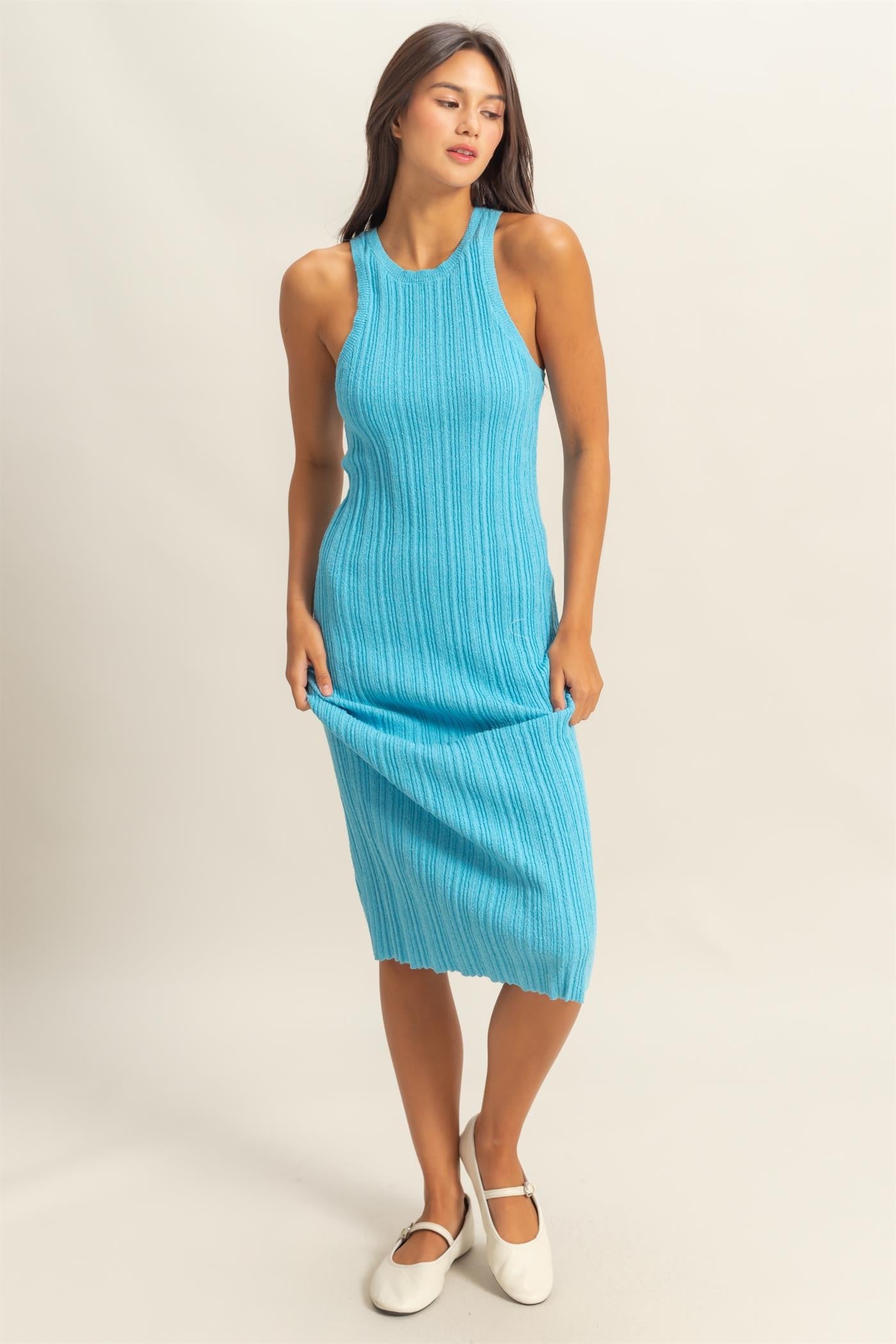 woman wearing a ribbed turquoise midi dress with a sleeveless design and a fitted silhouette