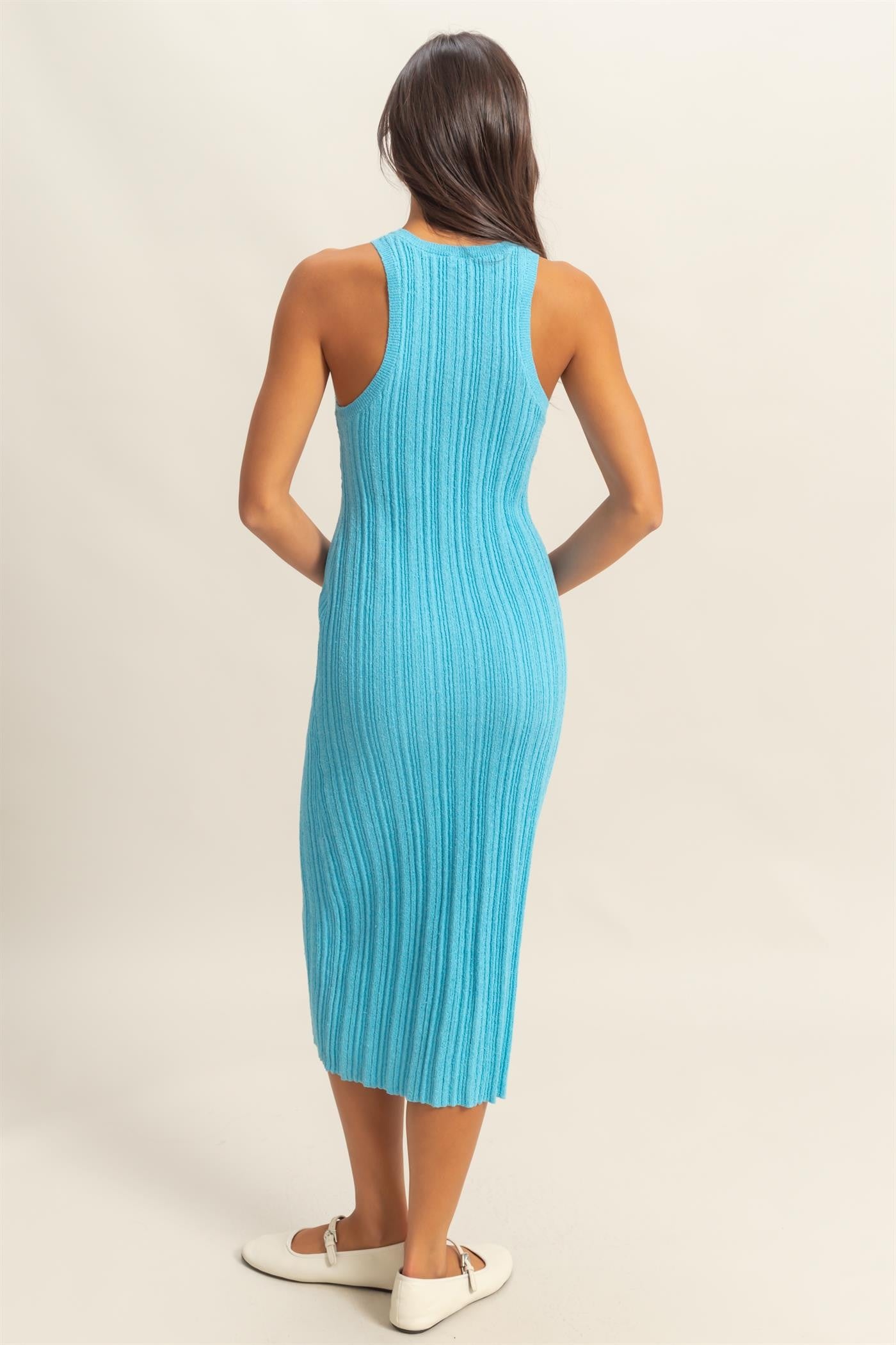 woman wearing a fitted ribbed midi dress in bright blue with a sleeveless design and side slits