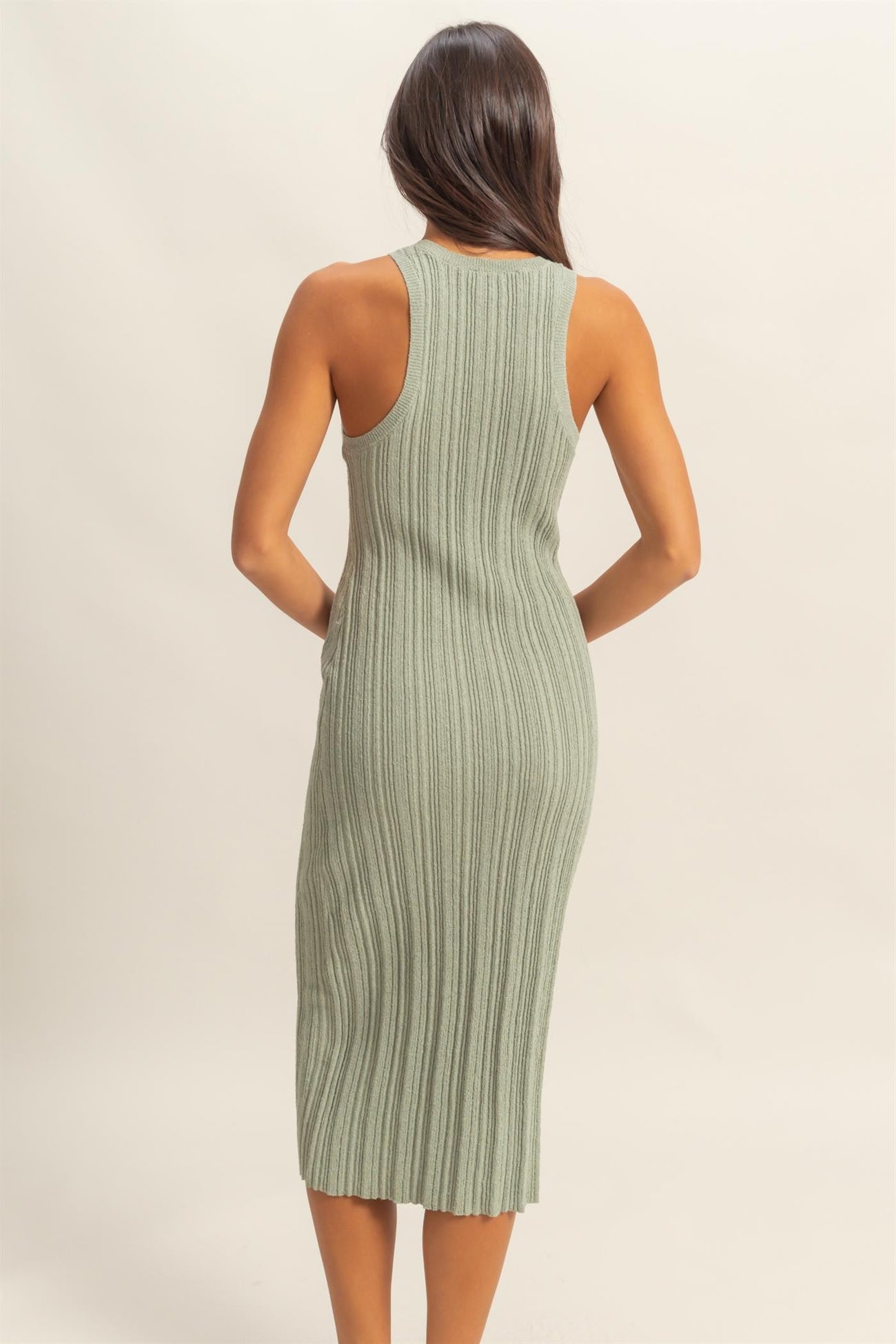 woman wearing a ribbed green midi dress with a fitted silhouette and backless design
