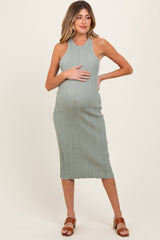 woman wearing a sage green ribbed maternity dress and holding her baby bump