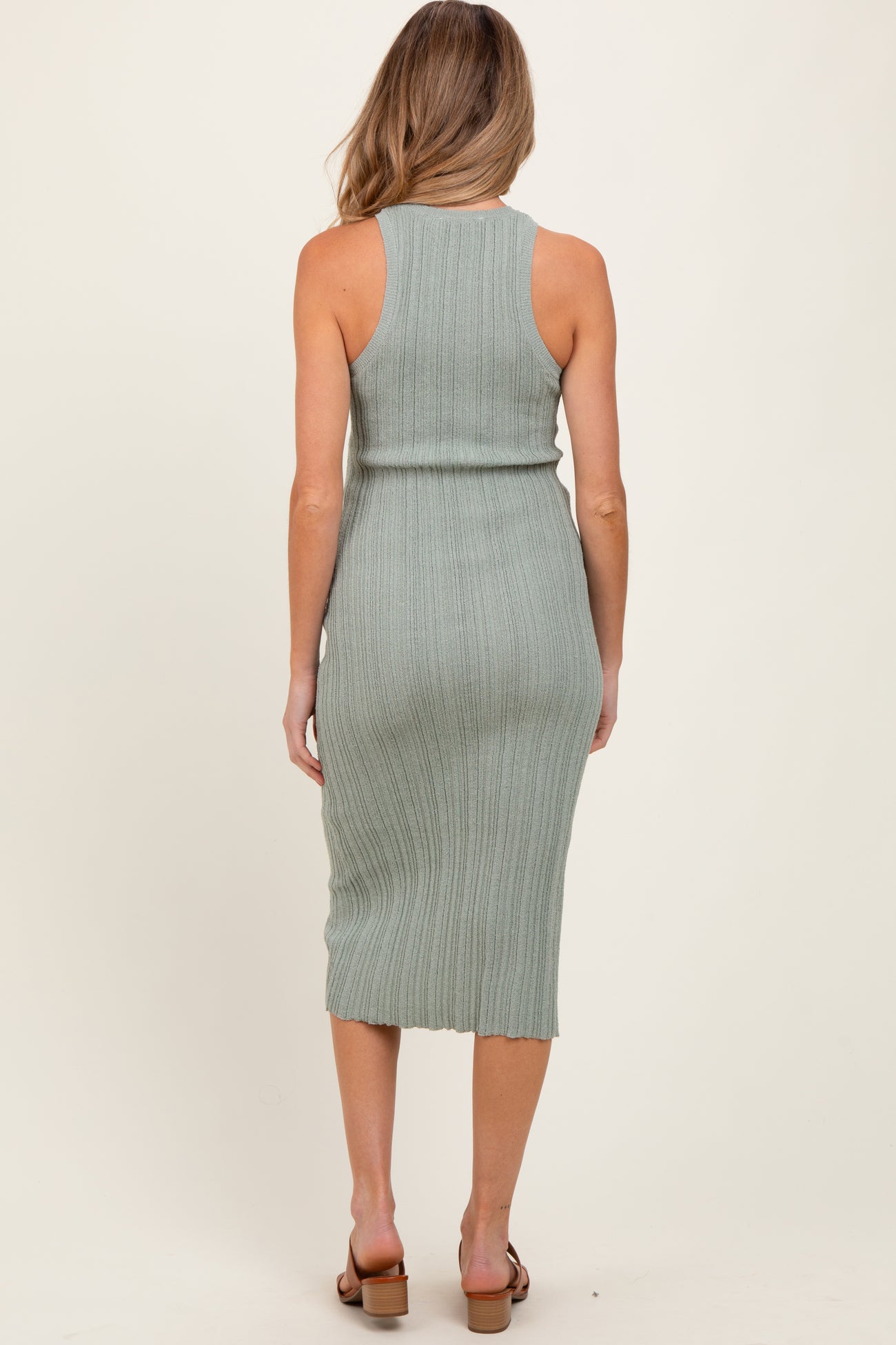 woman wearing a light green ribbed maternity dress with a fitted silhouette, seen from the back