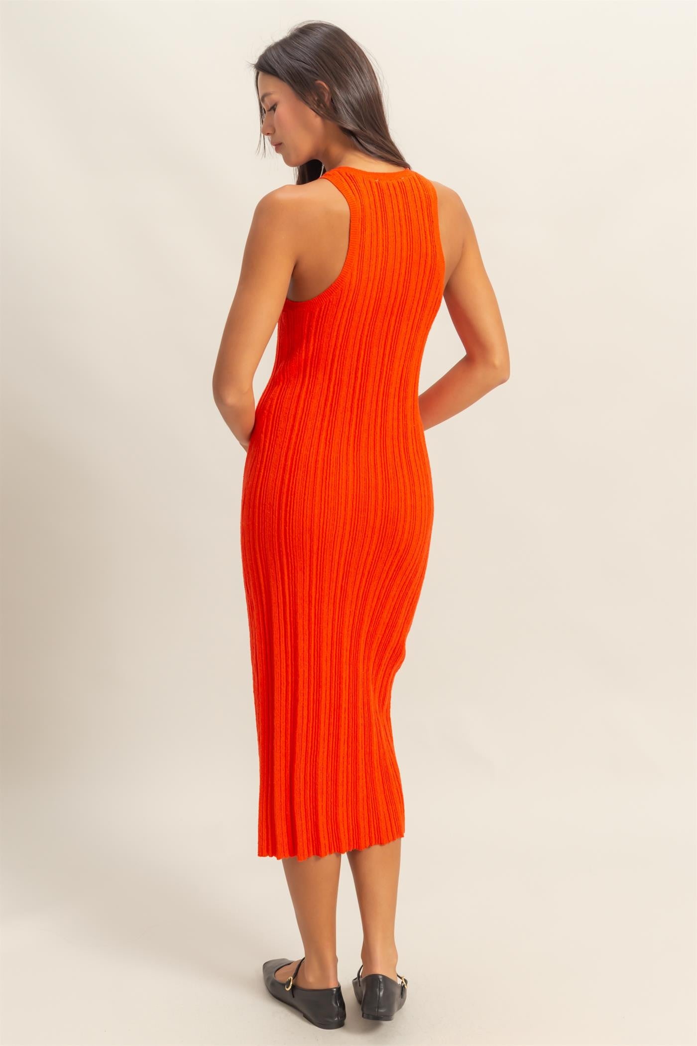 woman wearing a bright orange knitted midi dress with a fitted silhouette and ribbed texture
