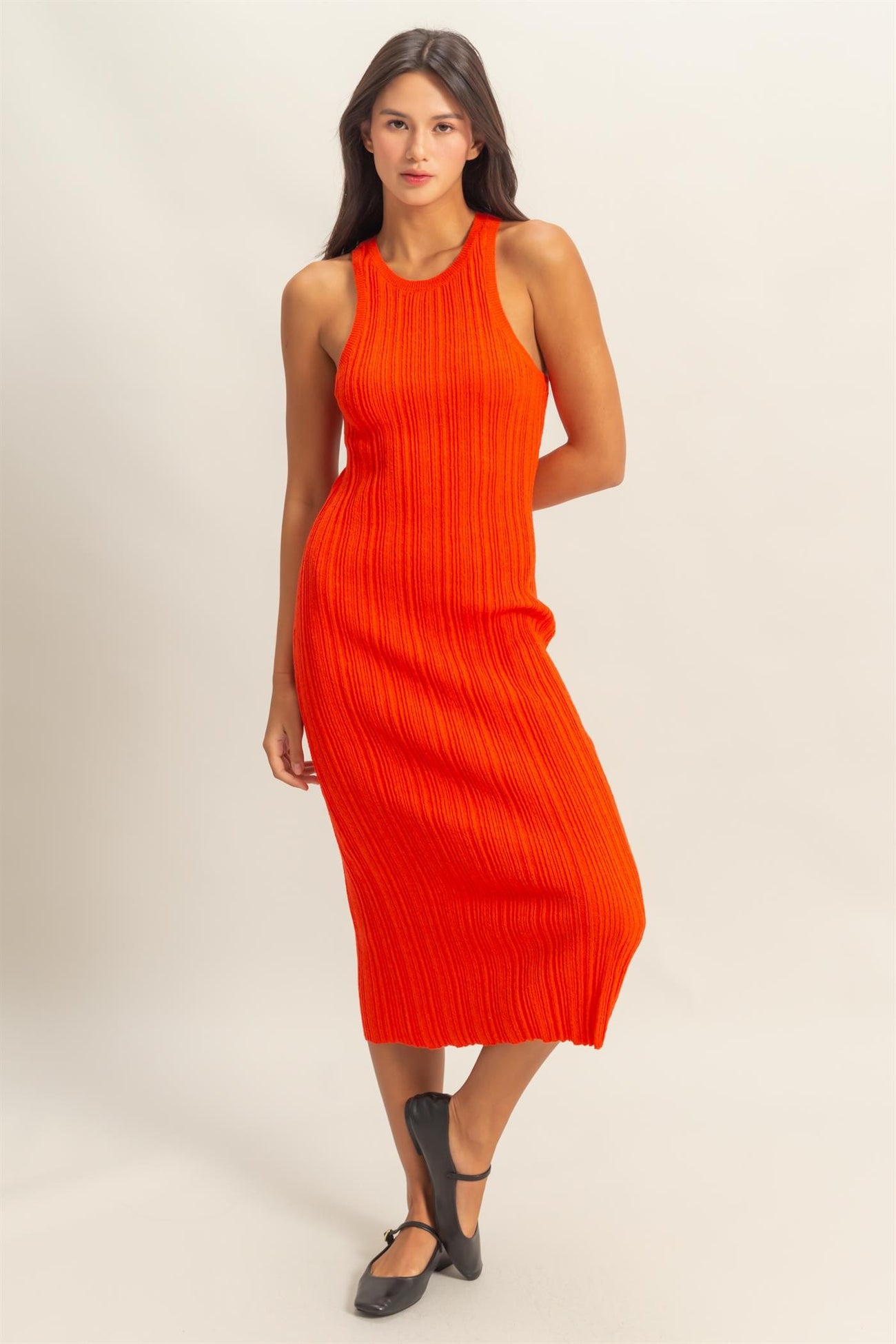 woman wearing a sleeveless ribbed midi dress in bright orange with a fitted silhouette