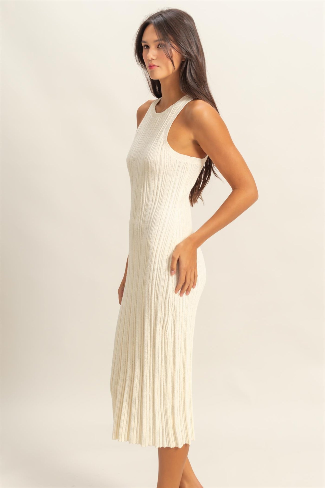 woman wearing a cream ribbed knit long dress with a fitted silhouette and sleeveless design