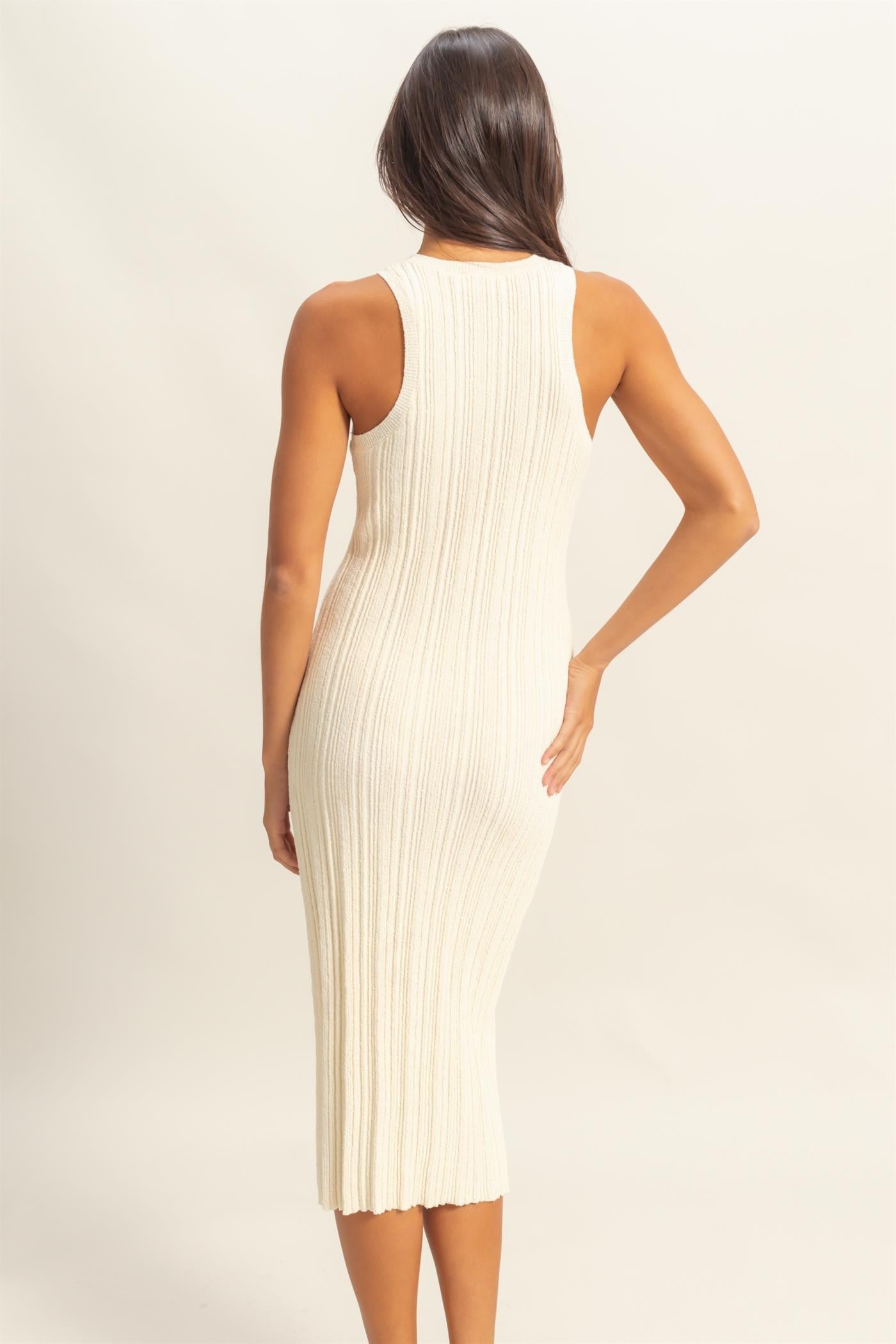 woman wearing a cream ribbed midi dress with a fitted silhouette and sleeveless design, seen from the back