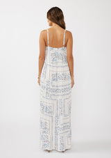 woman wearing a backless white maxi dress with blue floral patterns and thin straps