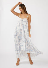 woman wearing a light blue and white floral maxi dress with a tie front and spaghetti straps