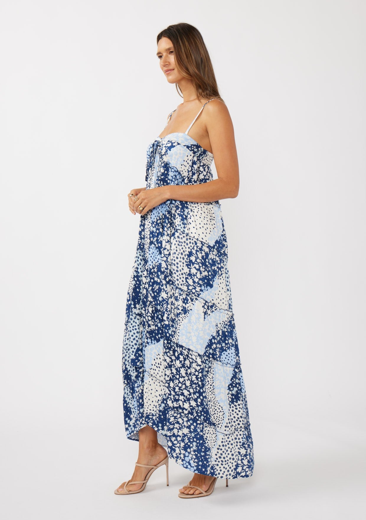 woman wearing a blue and white patterned maxi dress with spaghetti straps and a high-low hemline
