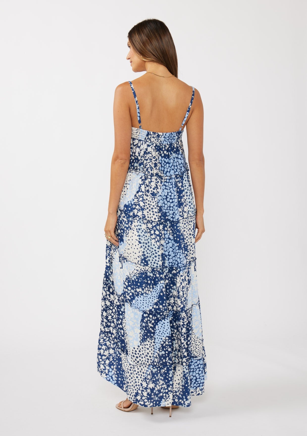 woman wearing a blue patterned maxi dress with thin straps and a fitted bodice, view from the back