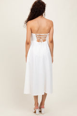 woman wearing a white strapless midi dress with a lace-up back and a flowy silhouette