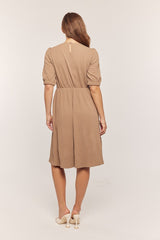 woman wearing a brown short sleeve dress with a textured pattern and a cinched waist seen from the back
