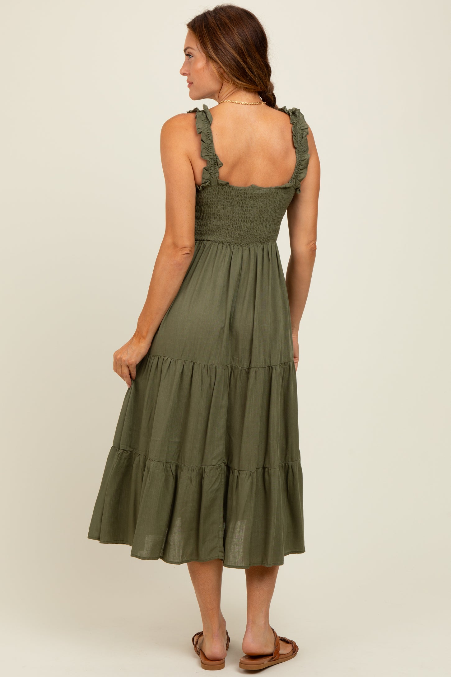 woman wearing an olive green tiered midi dress with ruffle straps, displaying a smocked bodice and a flowy skirt