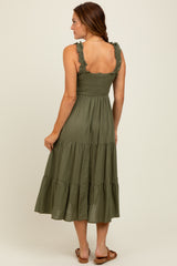 woman wearing an olive green tiered midi dress with ruffle straps, displaying a smocked bodice and a flowy skirt