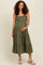woman wearing a green maternity dress with ruffled straps and a tiered skirt, showing her baby bump