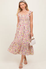woman wearing a floral smocked midi dress with ruffled sleeves and holding a small white purse