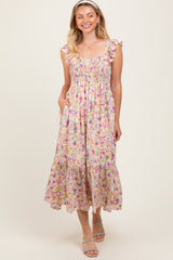 woman wearing a floral smocked midi dress with ruffle straps and pockets, standing and smiling