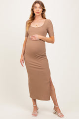 woman wearing a brown ribbed maternity dress with short sleeves and a side slit, gently holding her baby bump