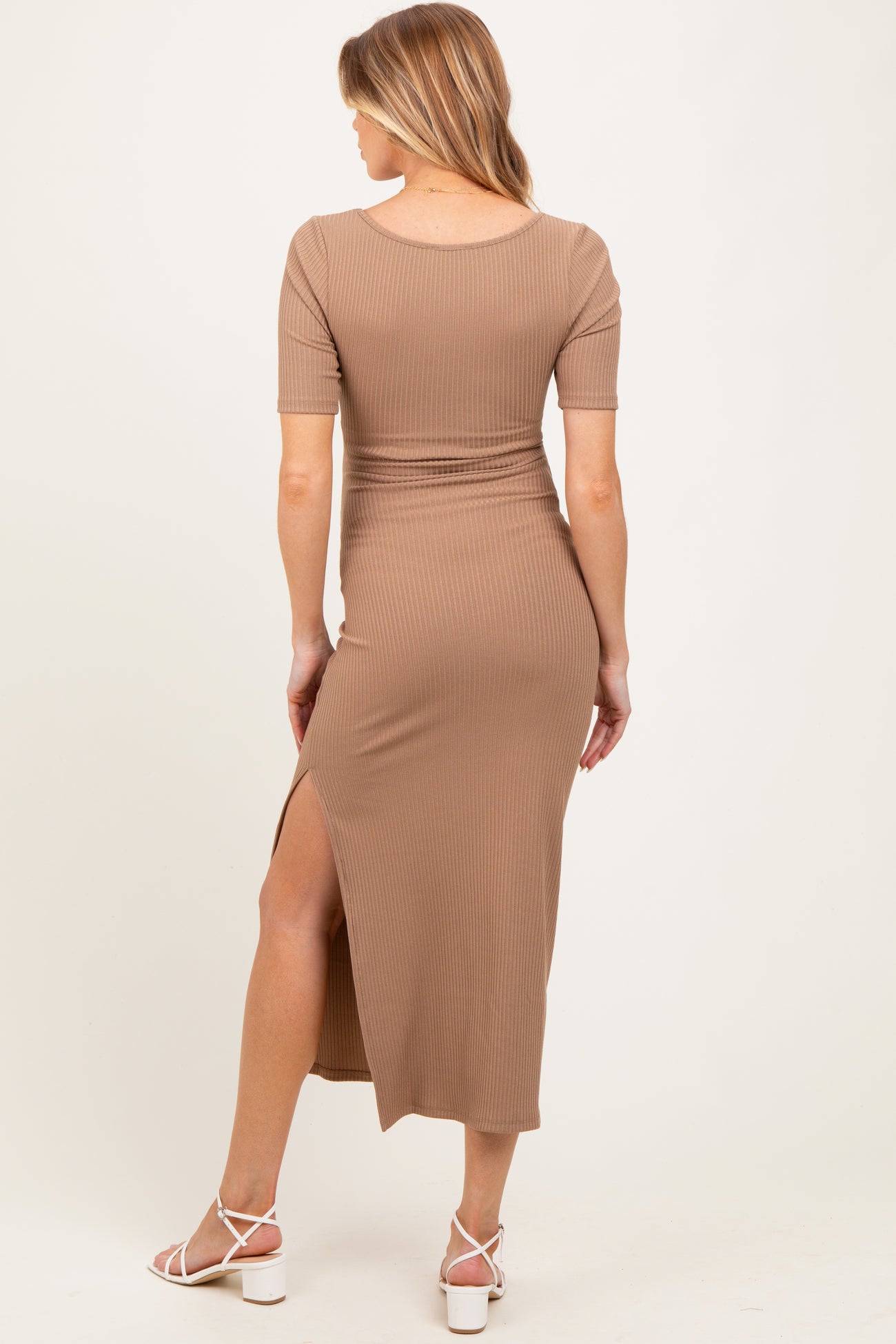 woman wearing a beige ribbed midi maternity dress with a side slit, showcasing a baby bump