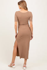 woman wearing a beige ribbed midi maternity dress with a side slit, showcasing a baby bump