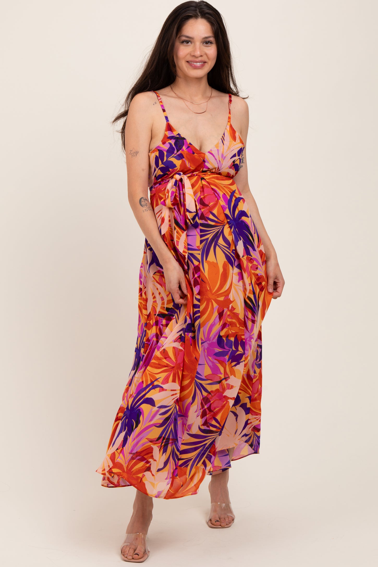 woman wearing a colorful floral maternity maxi dress with adjustable straps and a tied waist, highlighting her baby bump