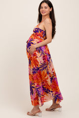 woman wearing a vibrant floral maxi maternity dress, showing her baby bump with a side pose