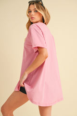 woman wearing a loose-fitting pink oversized t-shirt with short sleeves and a rounded hem