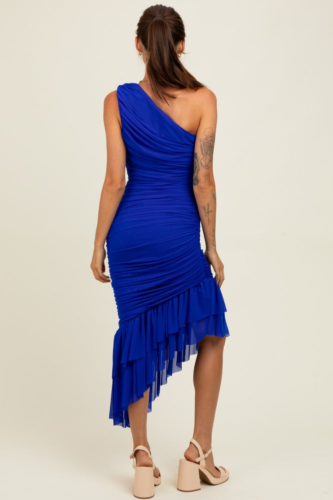 woman wearing a one-shoulder royal blue fitted dress with ruched detailing and a ruffled hem