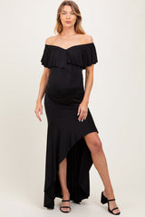 woman wearing a black off-the-shoulder maternity dress with ruffle details and a high-low hem, showcasing her baby bump