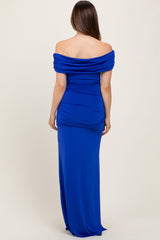 woman wearing a cobalt blue off-the-shoulder maternity dress with ruching and a long skirt