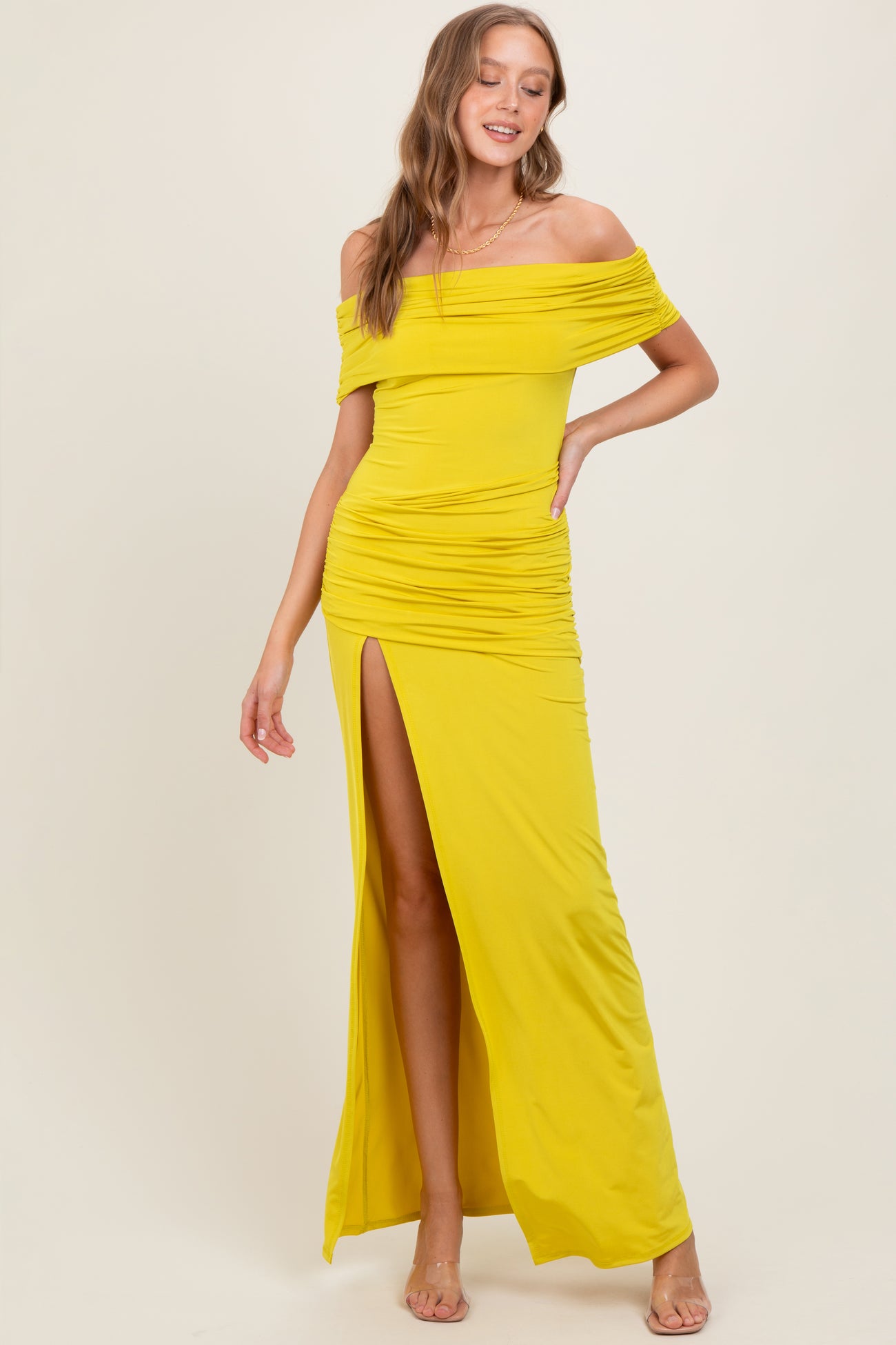 woman wearing a bright yellow off-the-shoulder maxi dress with ruched details and a thigh-high slit