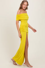 woman wearing a yellow off-the-shoulder evening gown with ruched details and a thigh-high slit