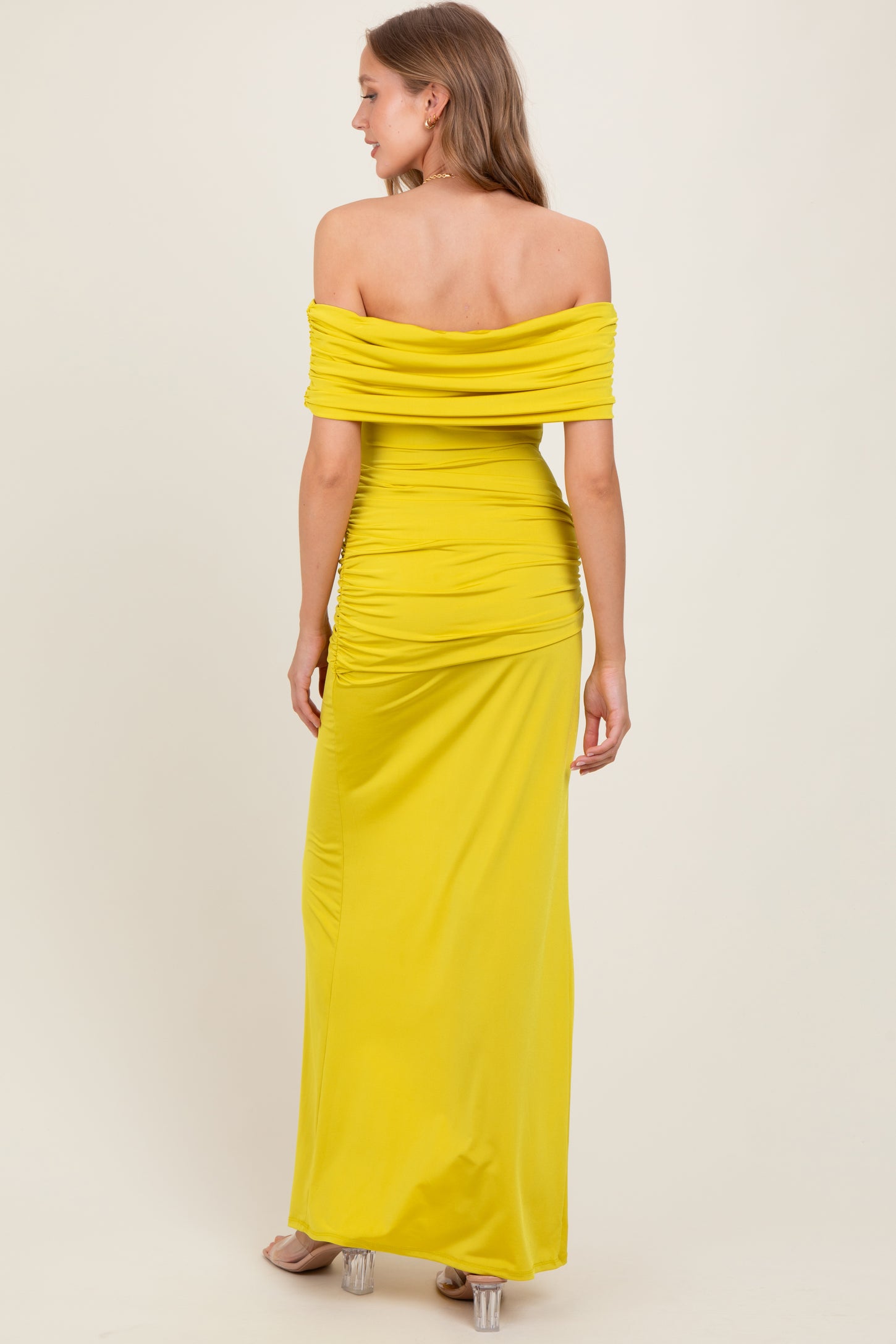 woman wearing a yellow off-the-shoulder maxi dress with ruching details and a fitted silhouette