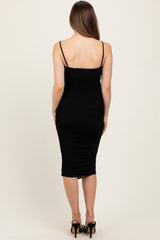 woman wearing a black ruched midi maternity dress with thin straps, showing off a pregnant baby bump from the back