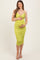 woman wearing a lime green fitted maternity dress with spaghetti straps and holding her baby bump