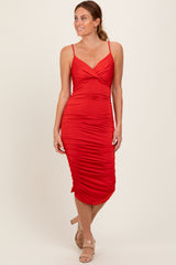 woman wearing a red ruched midi dress with adjustable spaghetti straps and a plunging neckline